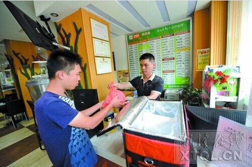 舒斌彬接受餐饮店的委托，配送一批外卖。(记者 陈旭东 摄)