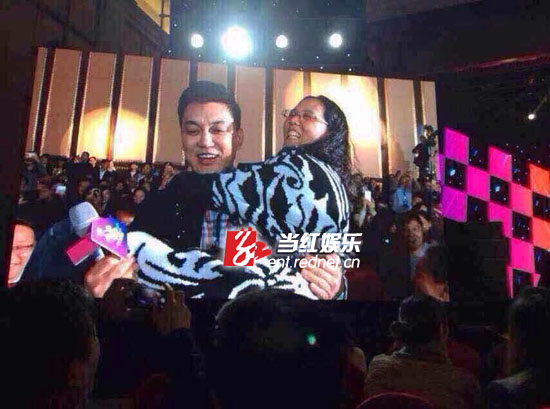 (李锐在现场抱着最后竞拍成功的女金主上台。)