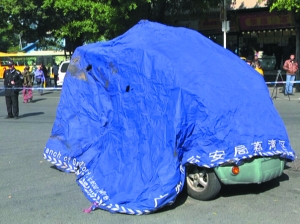 一辆城管执法电瓶车被蓝布盖起来，死亡小贩当时就是用这辆车送往医院。信息时报记者 周伟龙 摄