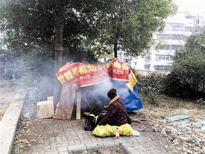 一居民在綠化帶旁熏臘肉。