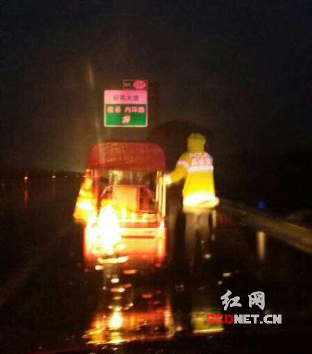民警冒着大雨将老人和车子护送下高速。