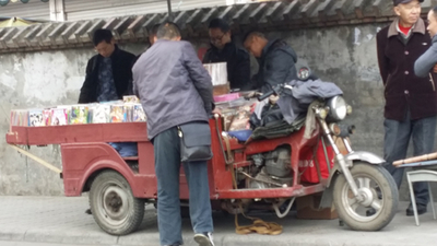 商家骑着三轮电动车售卖影碟
