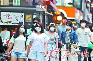 戴着口罩的游客经过韩国首尔明洞商业区。新华社发