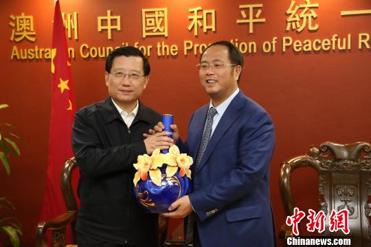 强卫向澳大利亚中国和平促进会会长黄向墨（右）赠送礼品。 赖海隆 摄