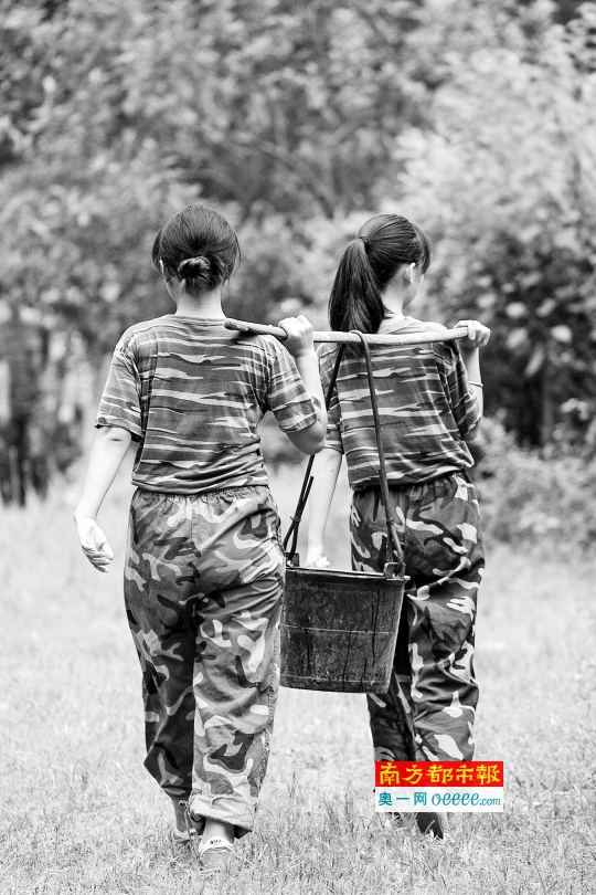 两名女生抬着粪水施肥。