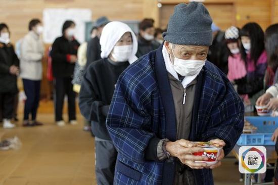 资料：2011年3月18日，在日本宫城县气仙沼市的一处避难所，日本老人手拿方便面作为午餐。（新华/EPA欧新）