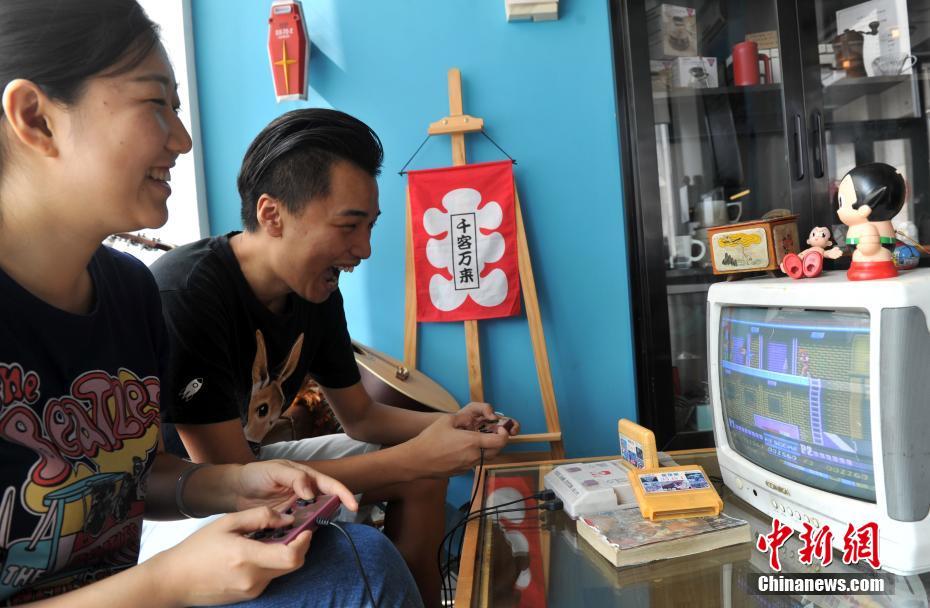 图为7月31日，店里的客人玩“小霸王”插卡游戏机
