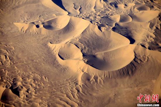 空中航拍浩瀚壮观的巴丹吉林沙漠，沙漠深处一处连片沙丘状似“龙头”，引人注目。