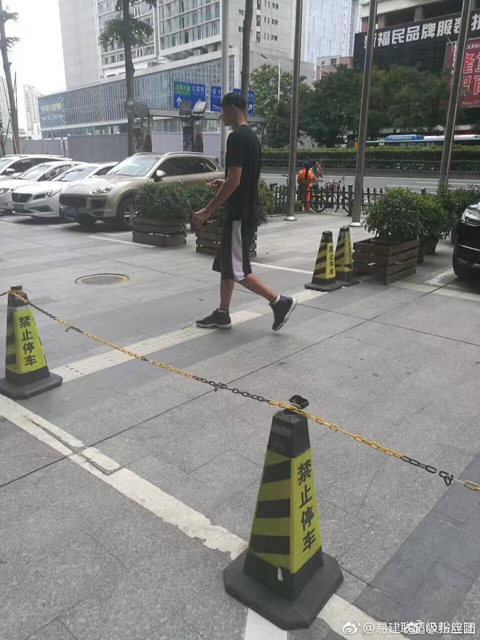 两人行走间自然地靠近彼此，荆灵侧头似在与阿联轻声交谈，阿联则微微侧耳倾听，举手投足间流露出无需言语的信任与亲昵，背景繁华的街景此刻也成了他们二人世界的温馨陪衬。