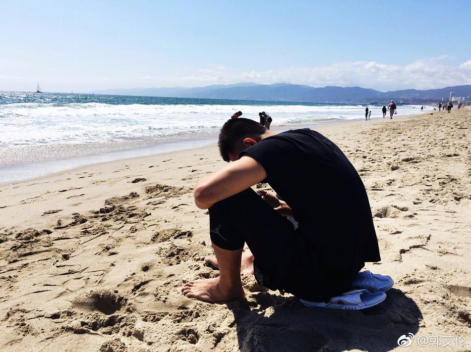 阳光洒在郭艾伦的笑脸上,他穿着休闲T恤,在海滩的微风中惬意地啃着金黄喷香的烤苞米,眼神里都是放松。