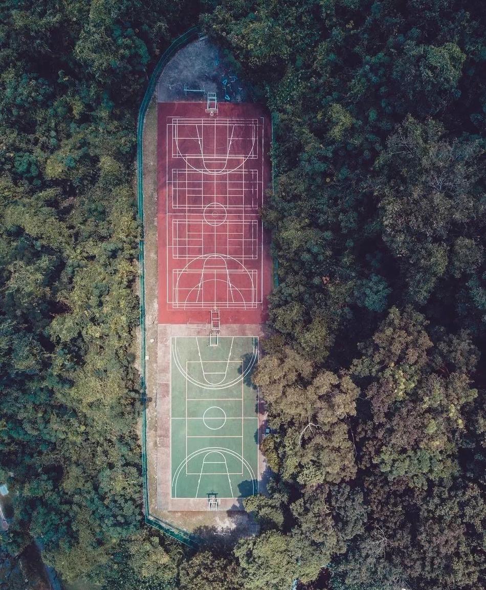 雨后，篮球场低洼处积水如镜，倒映出天空的晚霞和静止的篮架，现实与倒影虚实莫辨，营造出超现实的静谧美感。