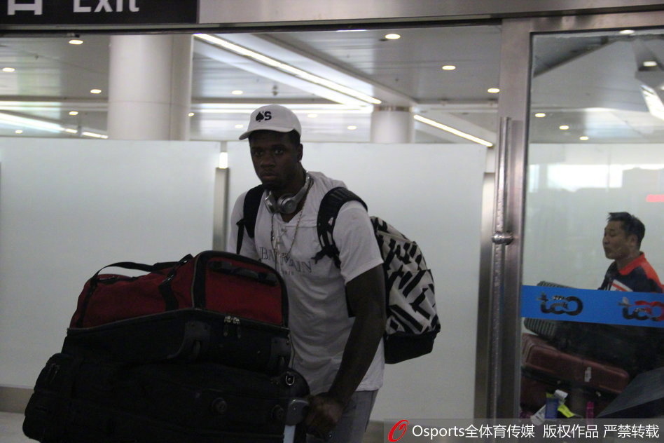 从行李提取处走出的琼斯，面带微笑与前来接机的工作人员握手，身旁的母亲目光温柔地注视着这一切。