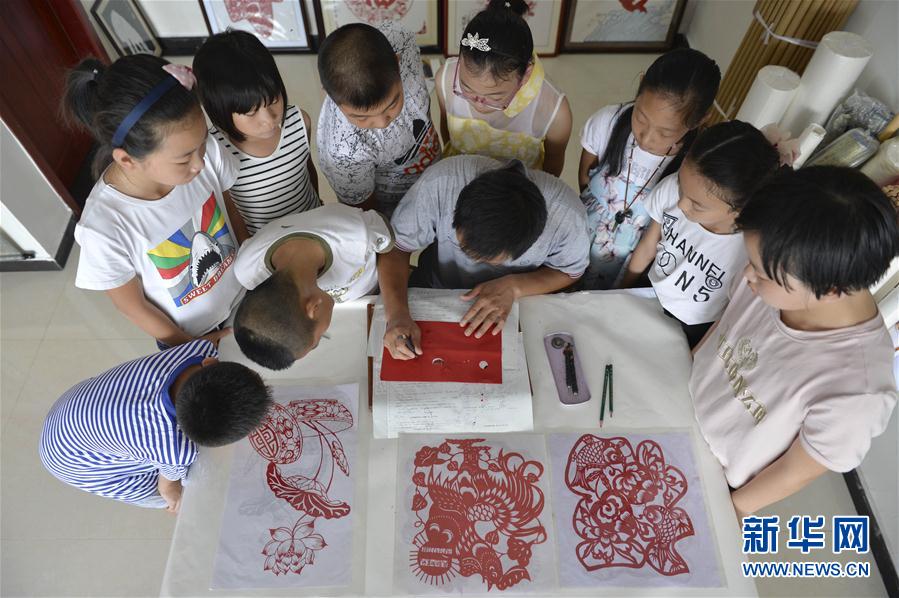 中)身旁,学习剪纸技艺.今年暑期,河北省南宫市民间艺人任书恒