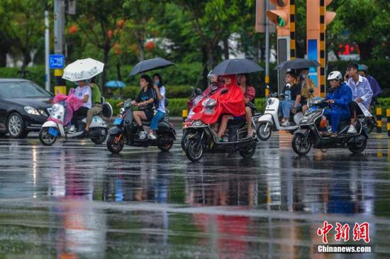 资料图：民众在雨中出行。 骆云飞 摄