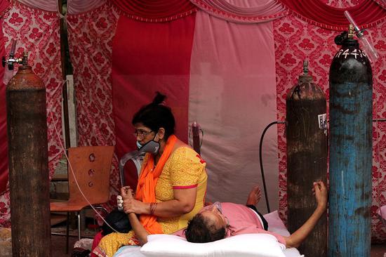 当地时间2021年5月6日，印度新德里，新冠肺炎患者躺在路边帐篷下吸氧。人民视觉 图