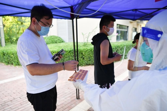  7月8日，志愿者（右）向西安市曲江新区紫汀苑社区居民发放核酸检测贴纸。新华社记者 张博文 摄