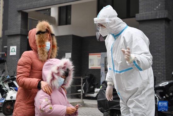 12月27日，在西安市雁塔区孟村小区，卢晨阳（右）向居民介绍核酸检测注意事项。新华社记者 张博文 摄