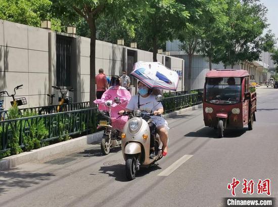 资料图： 6月4日，山东发布首个高温橙色预警。济南街头人们全副武装出行。赵晓 摄