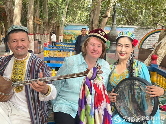 澳州80歲遊客麥基迪娜（中）在景區與藝人們合照。祖力菲亞·艾買提攝