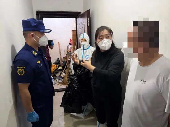  消防员与相关工作人员上门沟通清理工作。图源：北京消防