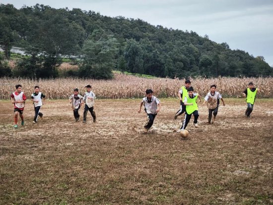 同学们在玉米地足球场踢球