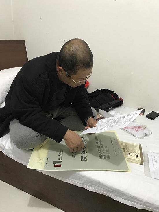 胡强在旅馆里面看医院的评估结果。澎湃新闻记者 袁璐 图