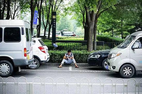 坐在街边停车位前的车位管理员 摄影 | 吕萌