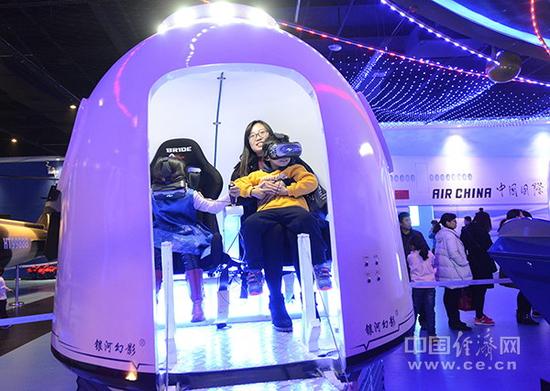 资料图片:观众在航空航天科技体验馆里体验载人航天器的返回舱。(图片来源:视觉中国)