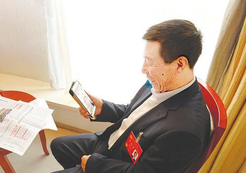 ▲北京:沙万里代表与繁峙县小砂河村村民视频通话。 本报记者李联军摄