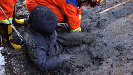 消防员清理小男孩腿部淤泥。图源：江西消防