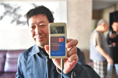 昨日上午,热力集团测温员樊广武在力源里北街2号院金地名京小区住户张雍家检测室内温度。A06-A07版摄影/新京报记者 吴江