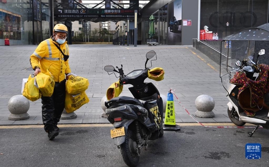  12月26日，外卖员在西安市南门外路边忙碌。新华社记者 陶明 摄