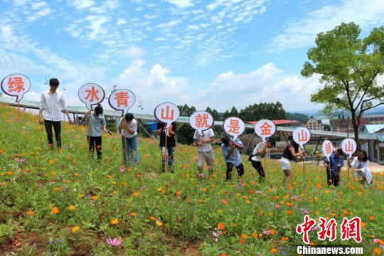图为学生举着写有“青山绿水同金山银山”的牌子。 杨孝勇 摄