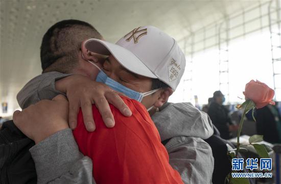 3月19日，在武漢天河機場，河南醫(yī)療隊隊員郭燕姿緊緊抱住丈夫王國曉。