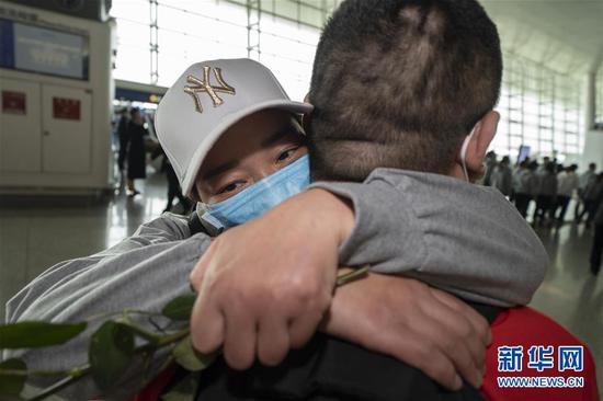 3月19日，在武汉天河机场，河南医疗队队员郭燕姿紧紧抱住丈夫王国晓。