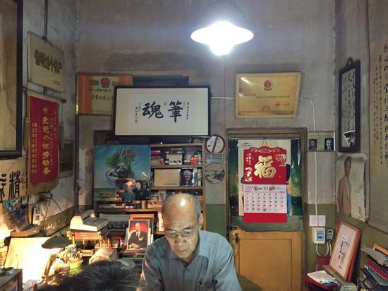从门缝看空空的小店,玻璃柜台背后的昏暗墙壁上有一幅字,那是一位修笔客人写的:笔魂。