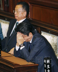 11月10日下午，日本首相安倍晋三出席表决跨太平洋伙伴关系协定（TPP）批准案及相关法案的众院全体会议，在座位上双手蒙住脸。内侧为农相山本有二。（共同社）