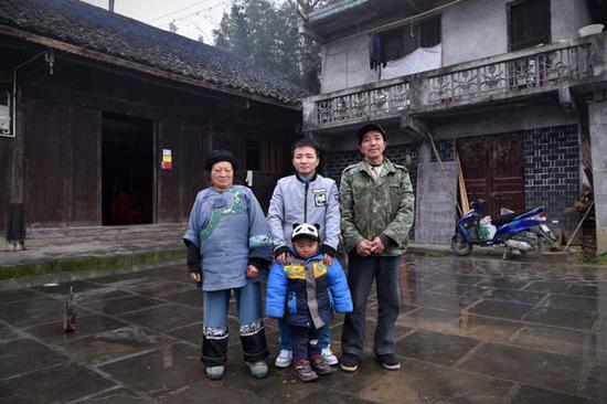 石欣(中)和他的父母、儿子在房前合影。