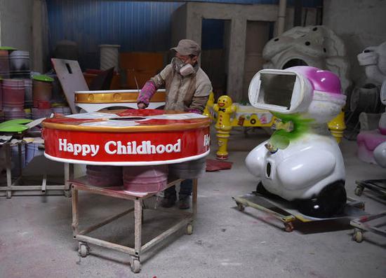 在广州番禺的工厂里,石欣在给动漫玩具喷漆。他说,有一次带儿子去县城玩,在街边见到一个玩具好像就是自己做的。