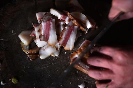 切腊肉,做午饭。这是石欣在外打工时最想念的家乡味道。