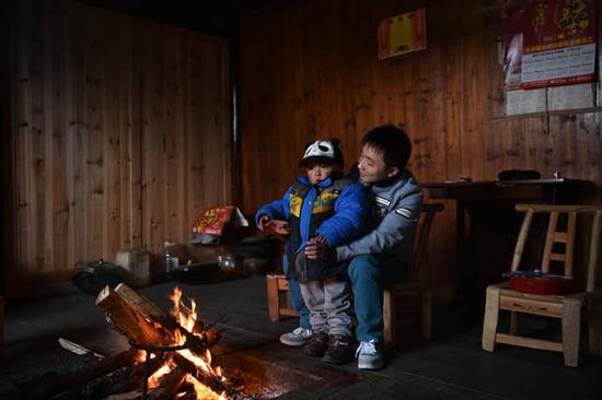 石欣把儿子抱回屋里,在柴火旁取暖,墙上贴着儿子上幼儿园后得的第一张奖状。