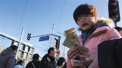 1月30日下午,一名黄牛将买来的20多张门票转手交给另一个黄牛进行出售。本版摄影/新京报记者 游弋
