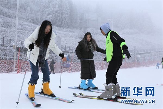 参与体验的青年学生在教练的帮助下进行双板滑雪练习。新华网 蔡连素 摄