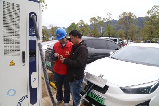 都匀荔波供电局组织青年服务队在荔波县小七孔东门停车场指导游客使用充电桩。王文涛 摄