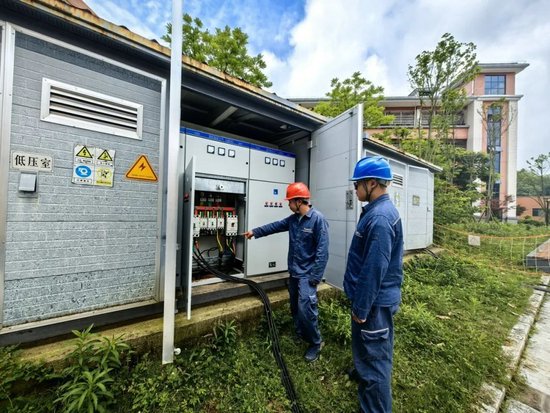 安顺镇宁供电局保供电人员在学校附近检查配电柜内线路情况。荣永康&nbsp; &nbsp;摄