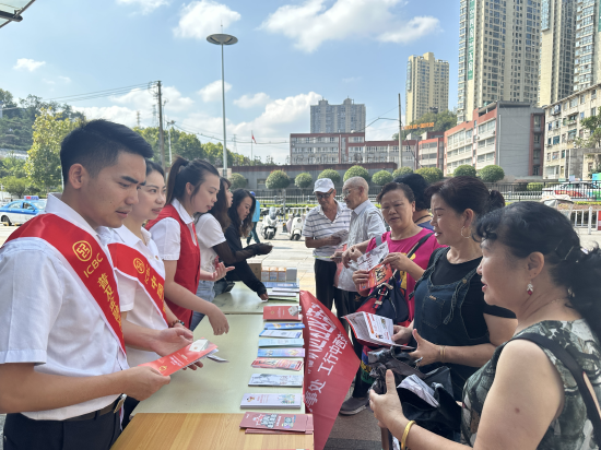 图为该行工作人员向过往市民发放金融知识宣传折页，进行金融知识普及