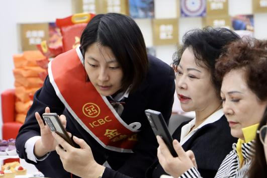 图为该行工作人员为客户讲解手机的摄影技巧