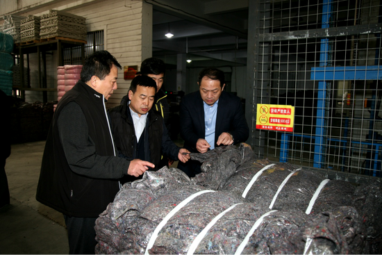 大连民善环保科技有限公司总经理韩永超为市慈善总会执行会长王胜利、副会长周建新介绍旧衣物加工处理过程