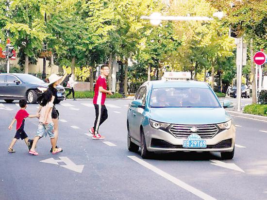 大人领着小孩横穿马路。