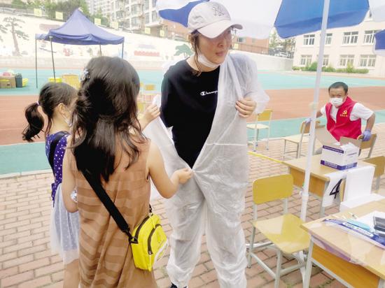 两个女儿帮王晶穿上防护服。